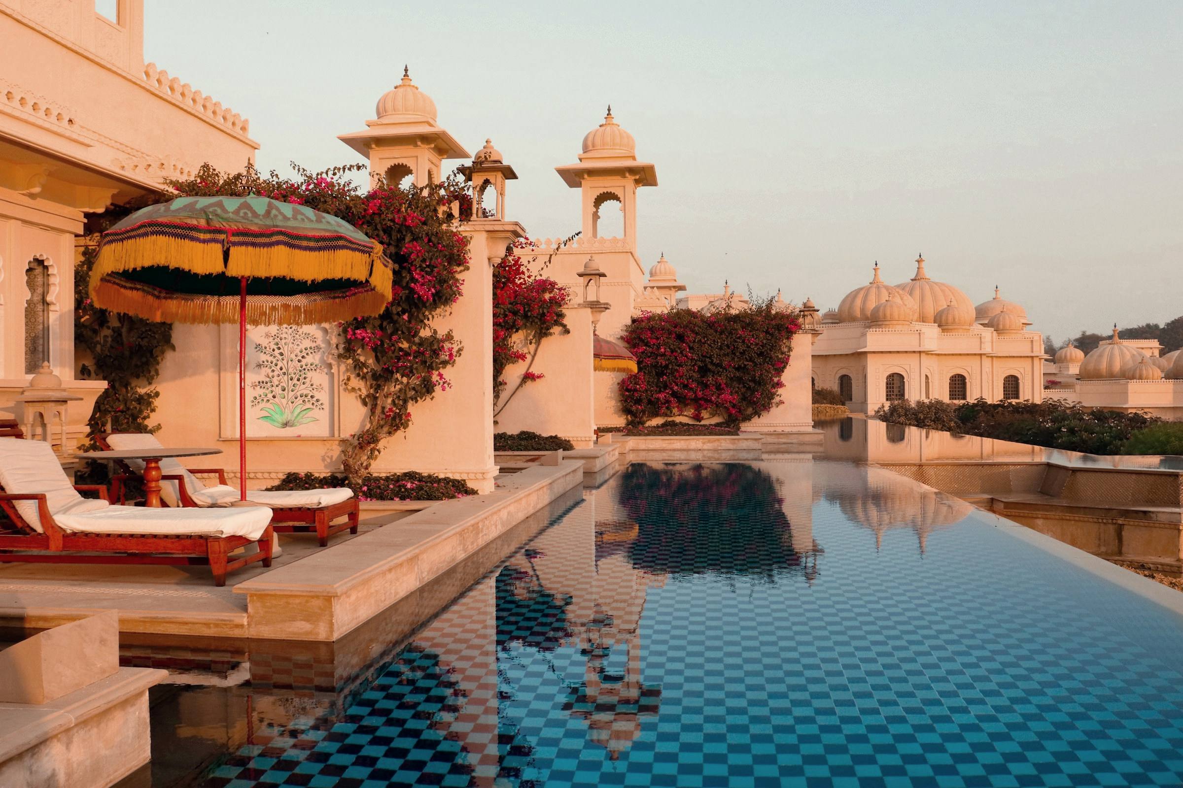 A palace-hotel pool with chhatris at dusk